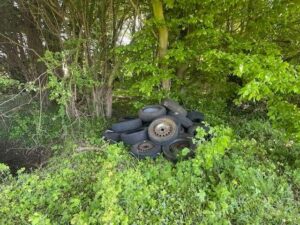 Ein Stapel illegal entsorgter Autoreifen mit Felgen liegt im Unterholz eines Waldstücks an einem Feldweg bei Bückeburg.