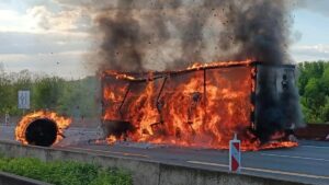 Flammen und dichter Rauch hüllen einen Sattelauflieger auf der Autobahn in ein Inferno