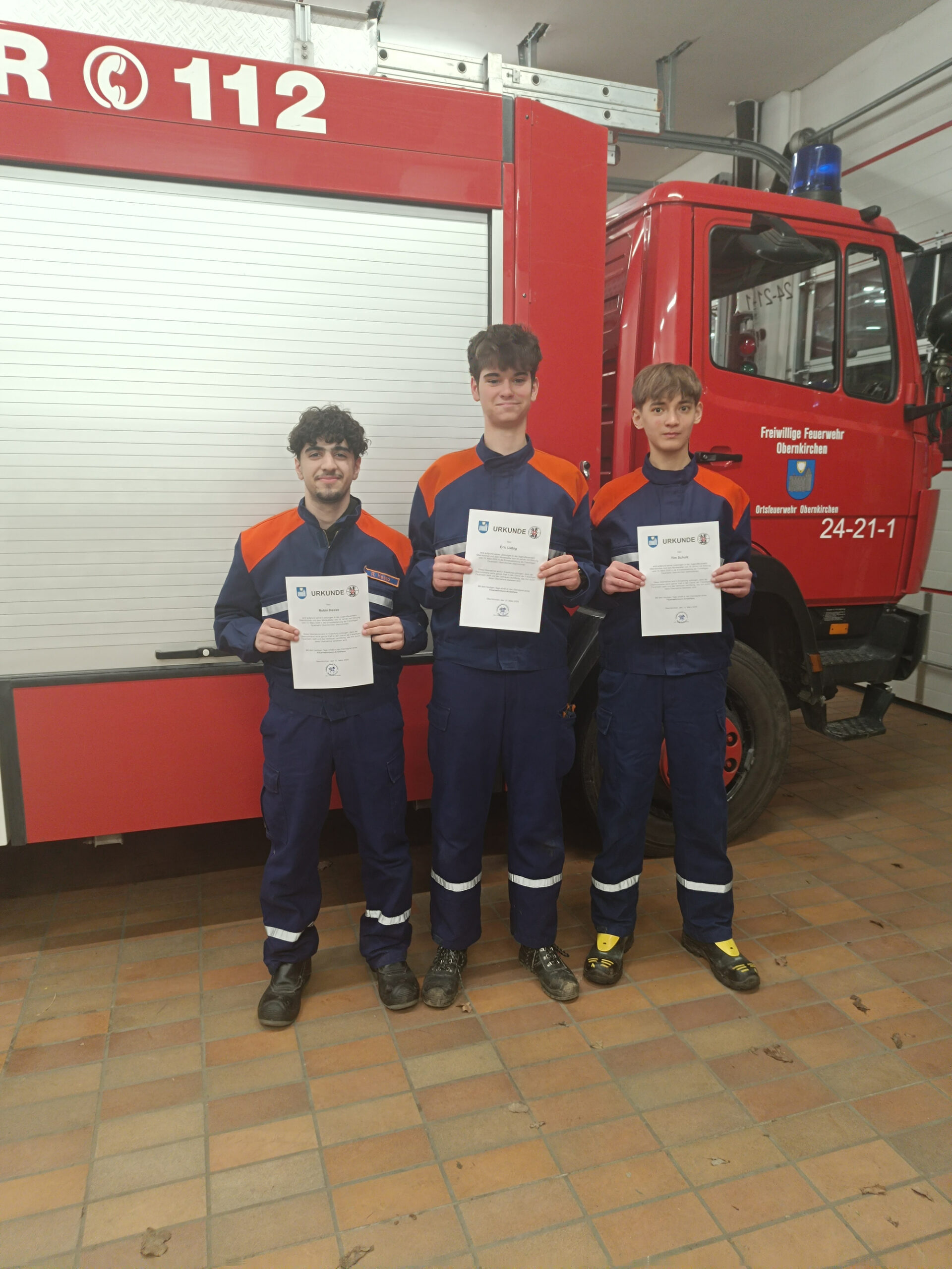 Drei Feuerwehrleute mit Urkunden