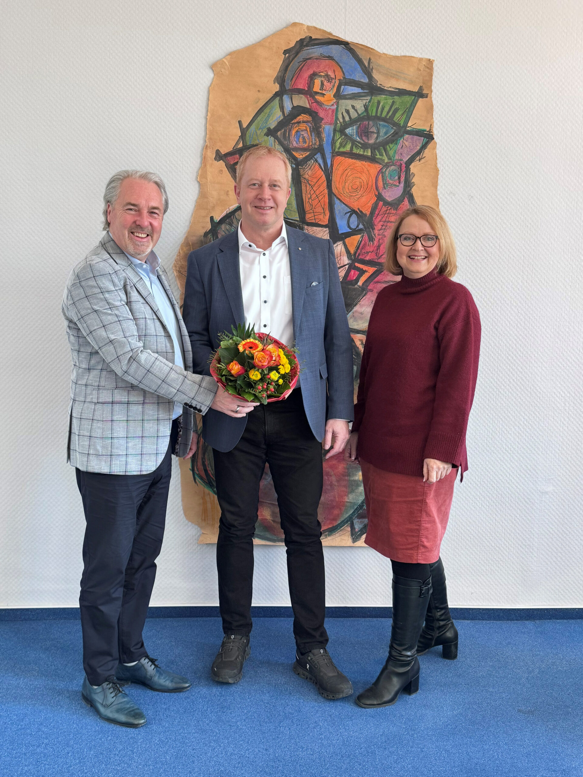 Samtgemeindebürgermeister Dr. Thomas Wolf, Schiedsmann Carsten Rose und Fachbereichsleiterin Saskia Kutscha stehen vor einem Wandbild.