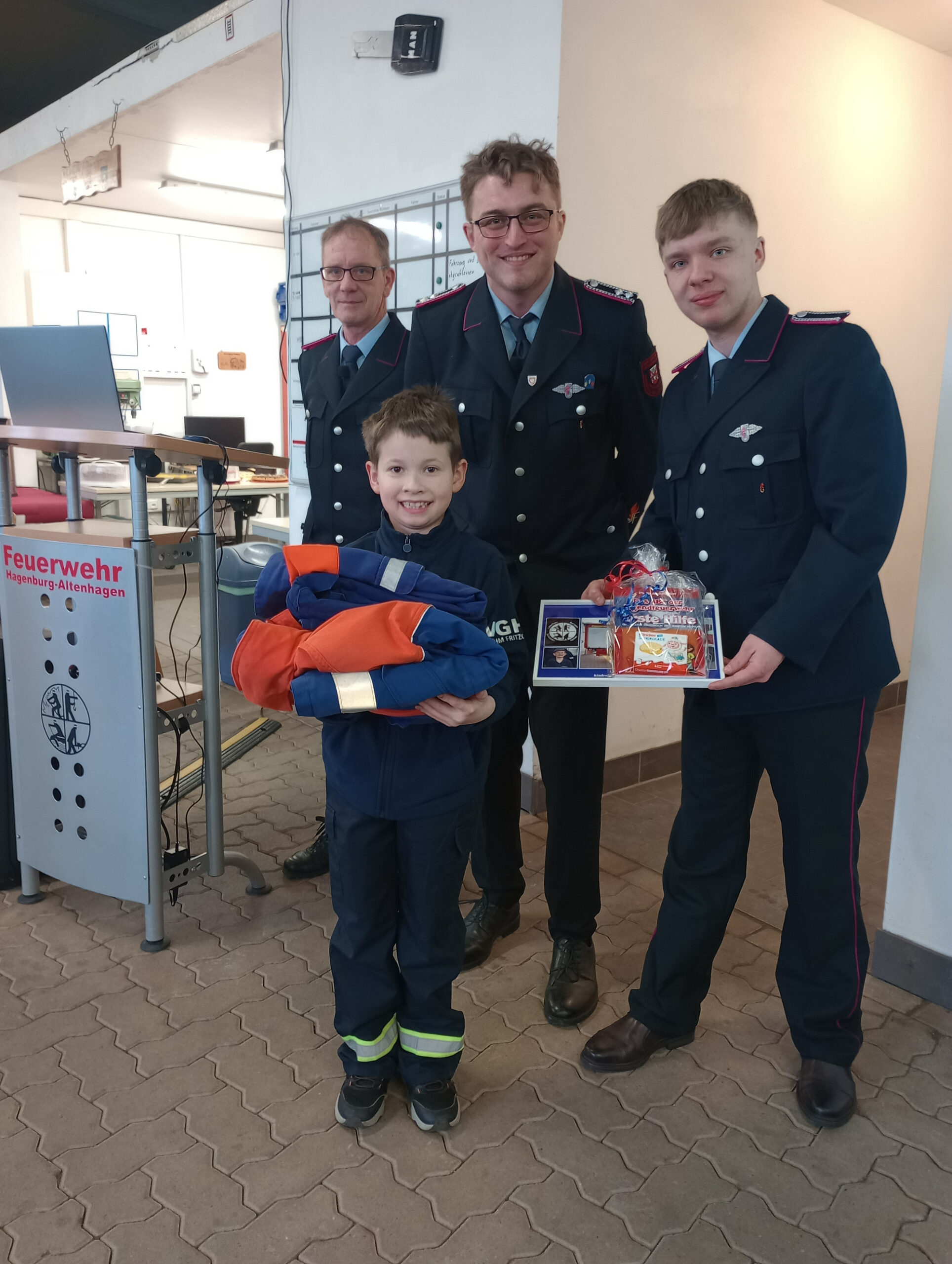 Matwij Dykun wechselt von der Kinder- in die Jugendfeuerwehr, umgeben von Jugendwart Leandro Wulferding und einem weiteren Mitglied.