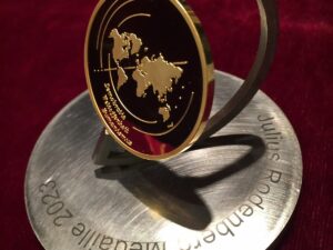 Eine goldene Medaille mit Weltkarten-Motiv auf einem silbernen Sockel.