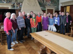 Eine Gruppe von Personen steht in einem historischen Saal hinter einem langen Tisch.