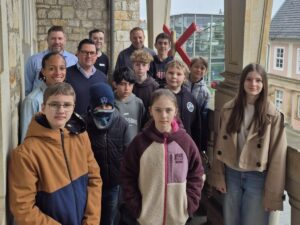 Eine Gruppe von Jugendlichen posiert für ein Gruppenfoto vor einer massiven Steinsäule.