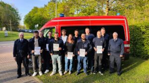Gruppe von Personen mit Urkunden vor einem roten Einsatzfahrzeug