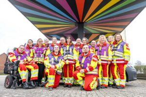 Personen in ASB-Uniformen unter einem farbenfroh gestreiften Zeltdach.