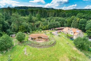 Luftaufnahme einer grünen Landschaft mit einem markanten Gebäude und Bienenhaus.