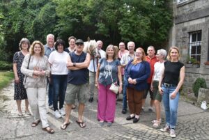 Eine Gruppe von Menschen steht für ein Foto zusammen im Freien vor einem Gebäude.